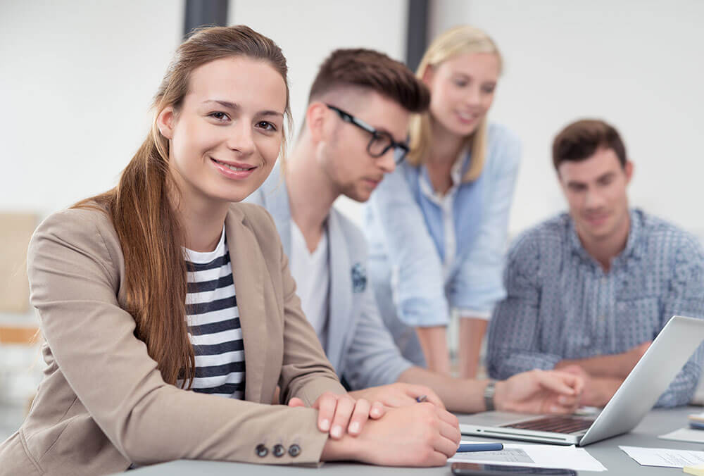 Vier junge Menschen an einem Tisch mit Notebook
